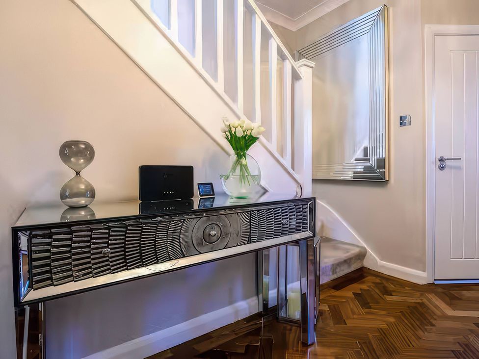 A hallway with a console table and vase of tulips at 7 Wolsey Mansions Northwood, Hertfordshire