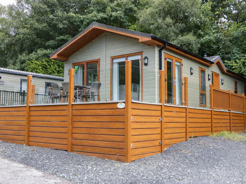 A log cabin with a deck and seating area at 19 Pony Meadow White Cross Bay near Troutbeck Bridge