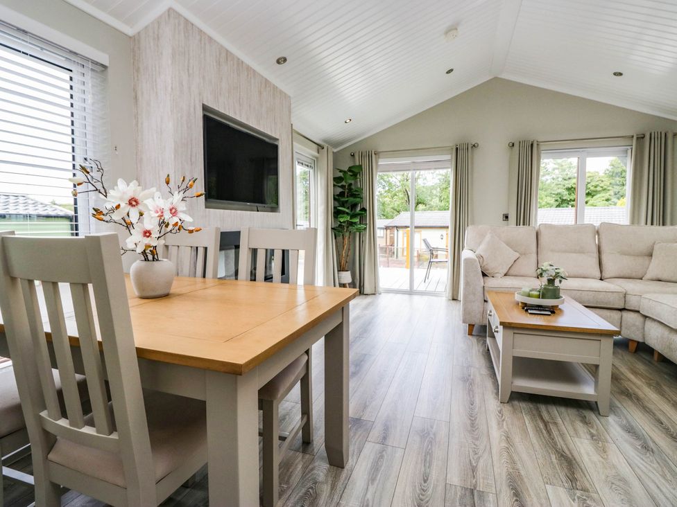 A living room with a dining area and sofa at 19 Pony Meadow White Cross Bay near Troutbeck Bridge