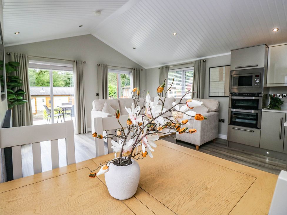 A living room with a dining table and a sofa at 19 Pony Meadow White Cross Bay near Troutbeck Bridge