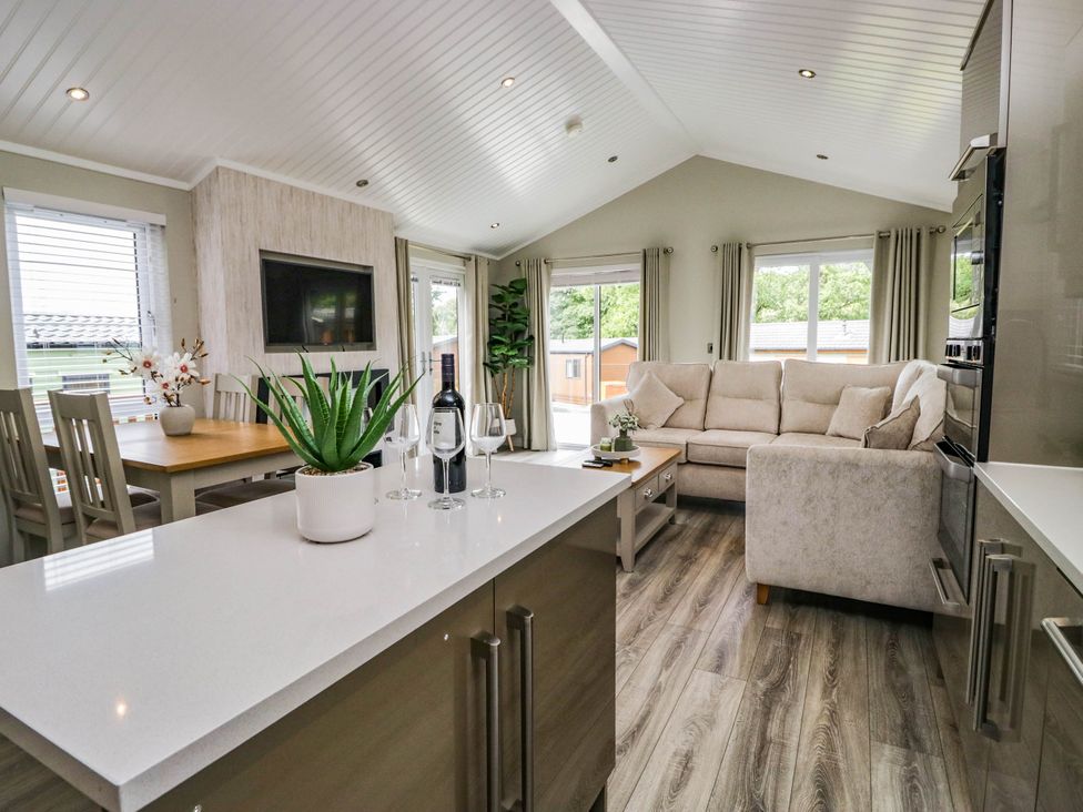 A living room with a sofa and dining area at 19 Pony Meadow near White Cross Bay