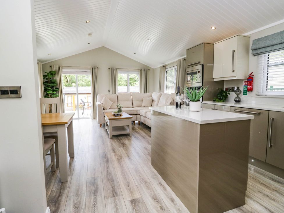 A living room with a sofa and dining table at 19 Pony Meadow in White Cross Bay near Troutbeck Bridge