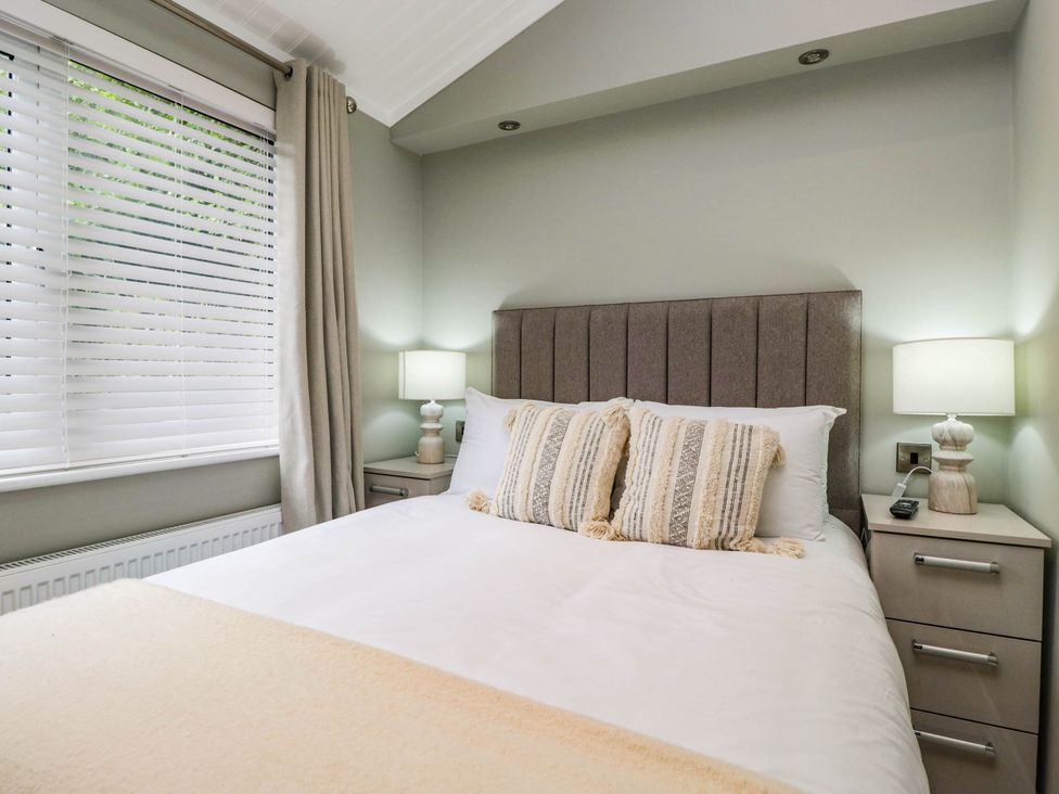 A bedroom with a bed and bedside table at 19 Pony Meadow White Cross Bay near Troutbeck Bridge