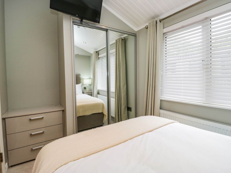 A bedroom with a bed and a wardrobe at 19 Pony Meadow near White Cross Bay