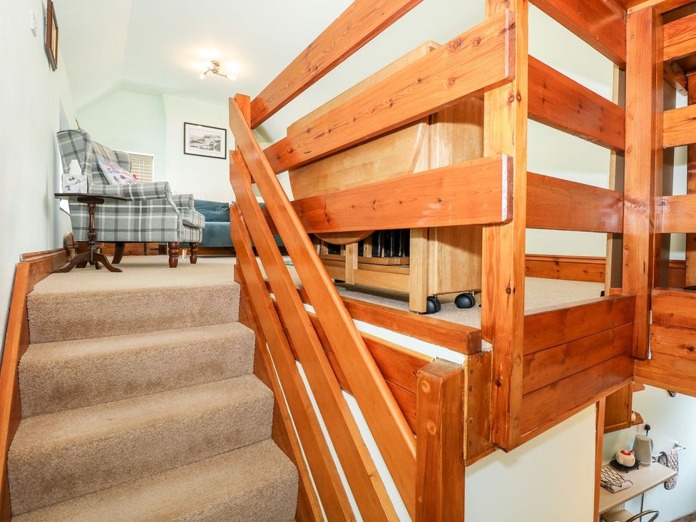 A staircase with wood features and a sofa at Beck Cottage Sheringham