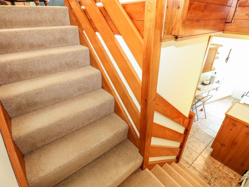 A staircase with carpet and wooden railing at Beck Cottage in Sheringham