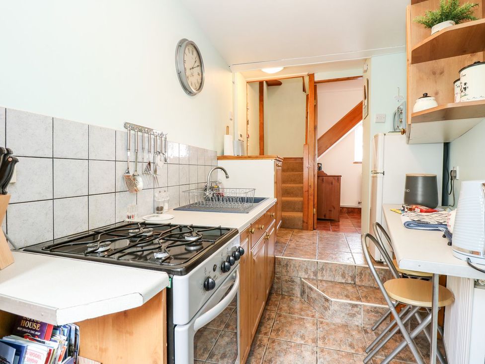 A kitchen with a gas stove and sink at Beck Cottage in Sheringham