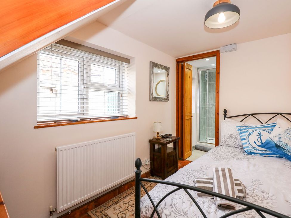 A bedroom with a bed and shower at Beck Cottage in Sheringham