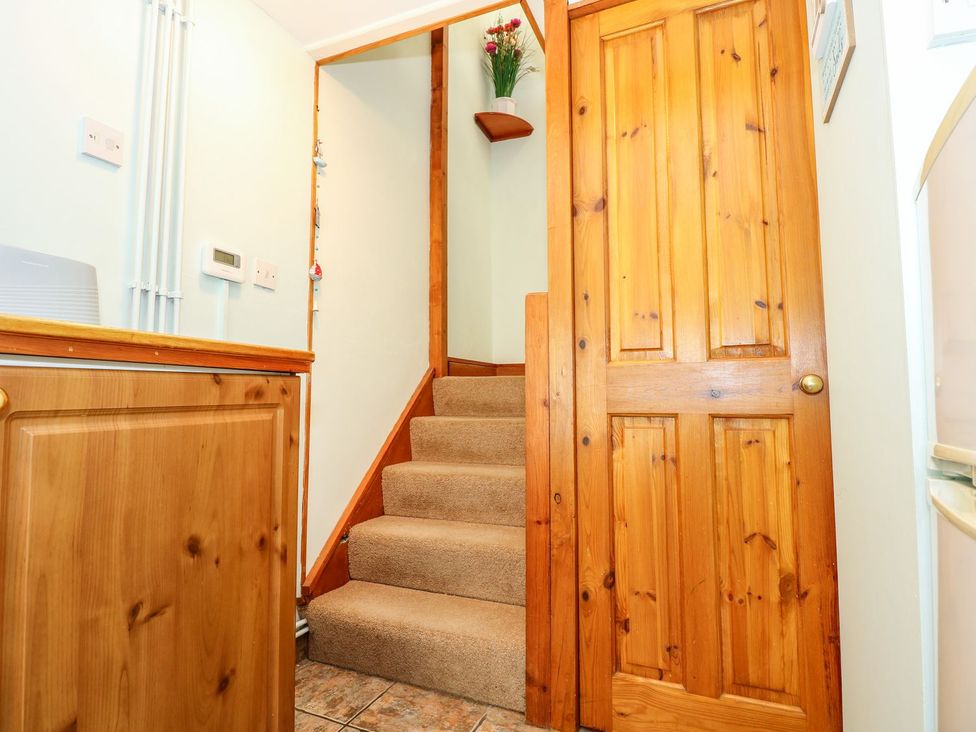A staircase and wooden door in a hallway at Beck Cottage in Sheringham