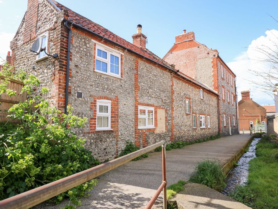 A stone and brick building with windows on the side at Beck Cottage in Sheringham