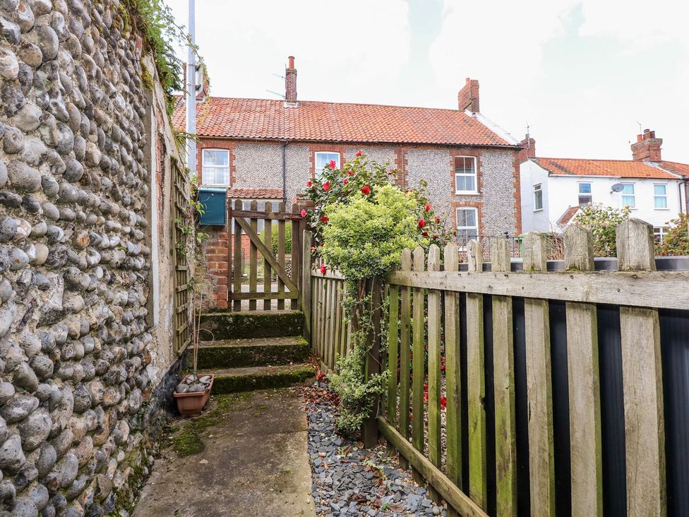 A garden pathway with a wooden gate at Beck Cottage in Sheringham