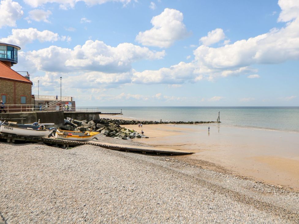 A beach with boats and a pier at Beck Cottage in Sheringham