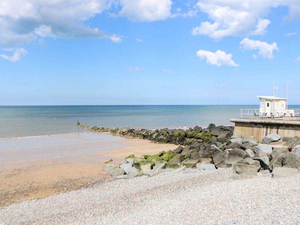 A beach with rocks and a pier at Beck Cottage in Sheringham