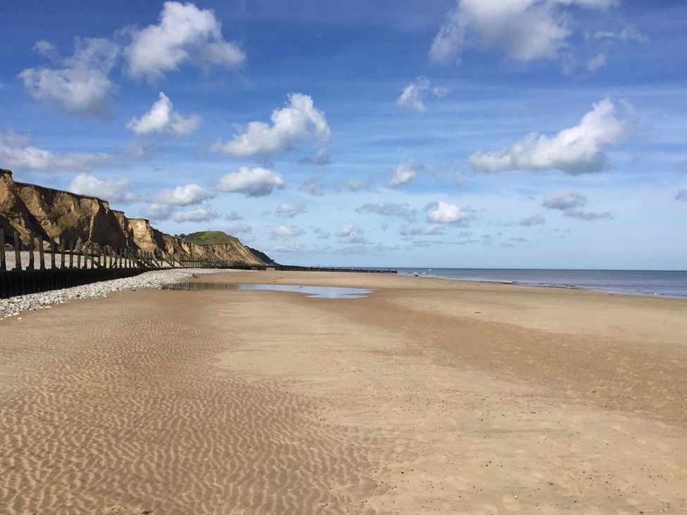 A beach with cliffs and clouds at Beck Cottage in Sheringham