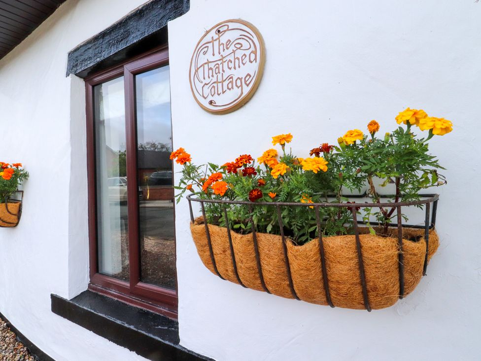 A window with flower boxes and a sign at The Thatched Cottage in Preston