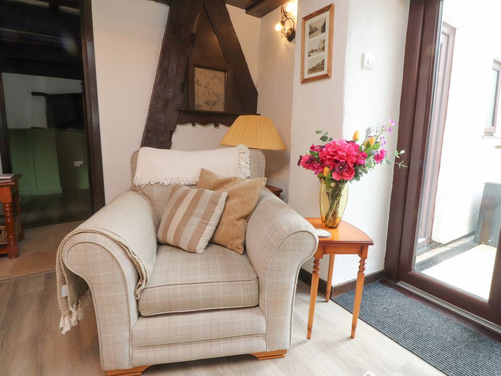 A living room with an armchair and a flower vase at The Thatched Cottage in Preston