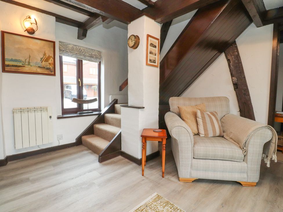 A sitting room with an armchair and staircase at The Thatched Cottage in Preston