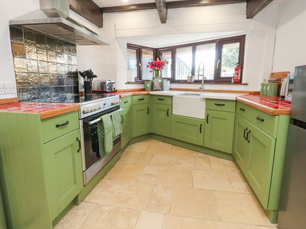 A kitchen with green cabinets and a sink at The Thatched Cottage in Preston
