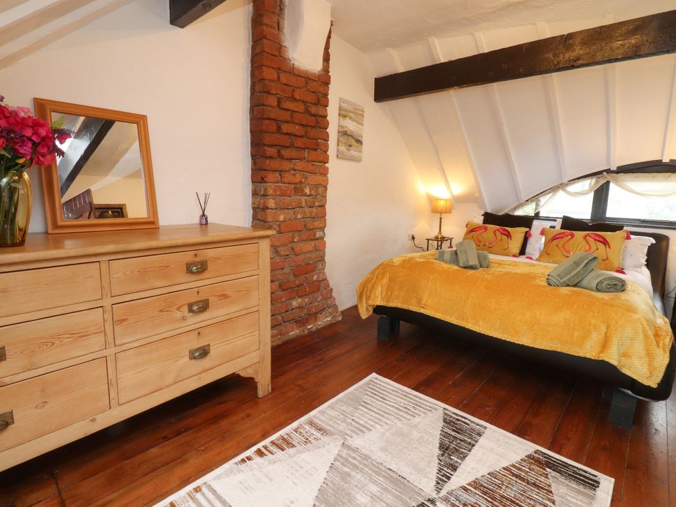 A bedroom with a bed and dresser at The Thatched Cottage in Preston