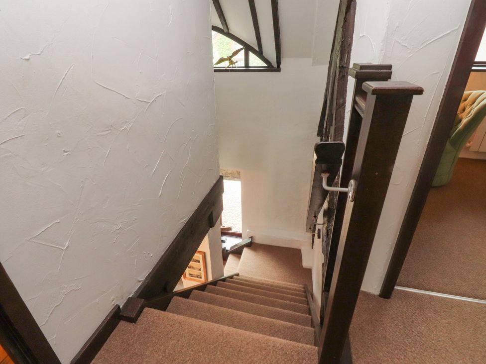 A staircase leading down with a banister at The Thatched Cottage in Preston