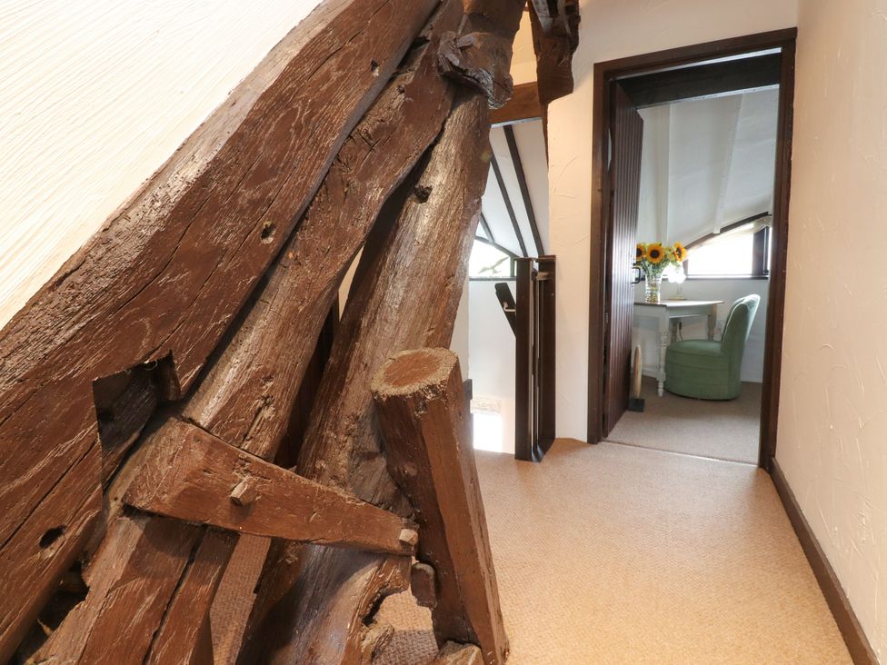 A hallway with wooden beams and a doorway leading to a room with a desk at The Thatched Cottage in Preston