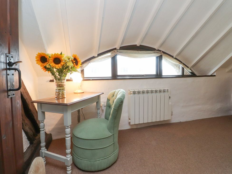 An attic with a table and chair near a window at The Thatched Cottage Preston