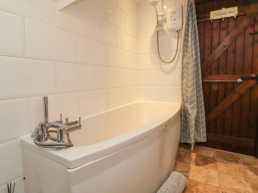 A bathroom with a bathtub and shower unit at The Thatched Cottage in Preston