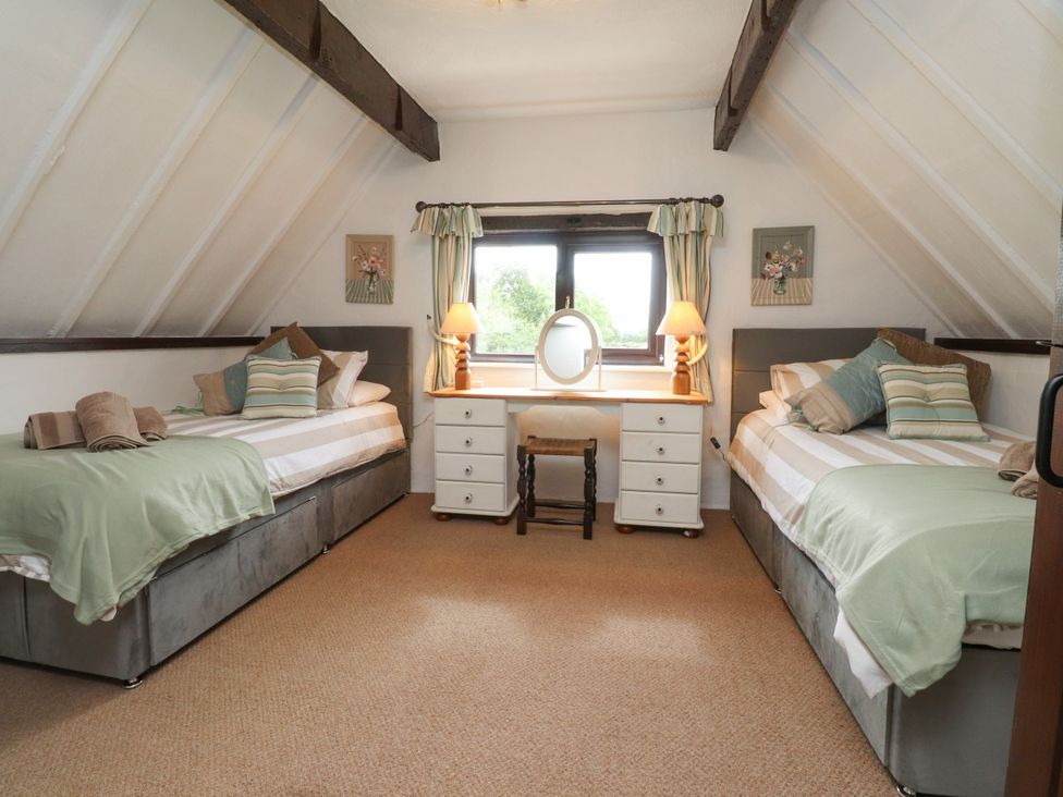 A bedroom with two beds and a desk at The Thatched Cottage in Preston