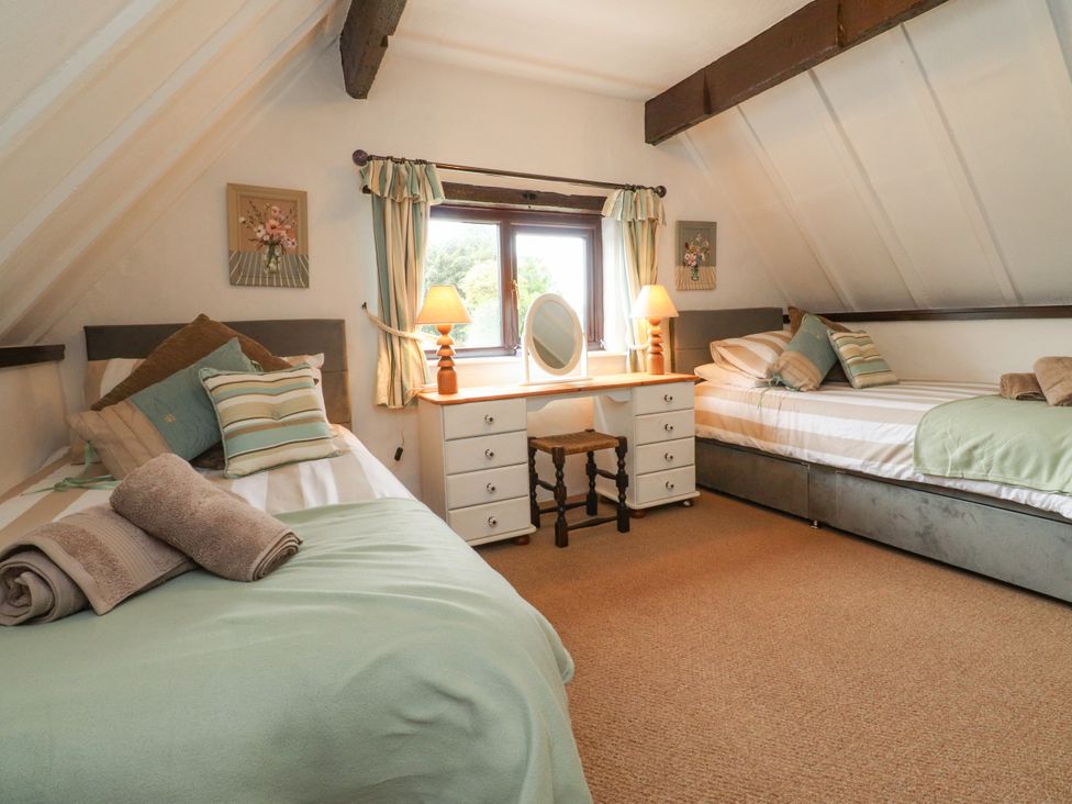 A bedroom with two beds and a desk at The Thatched Cottage Preston