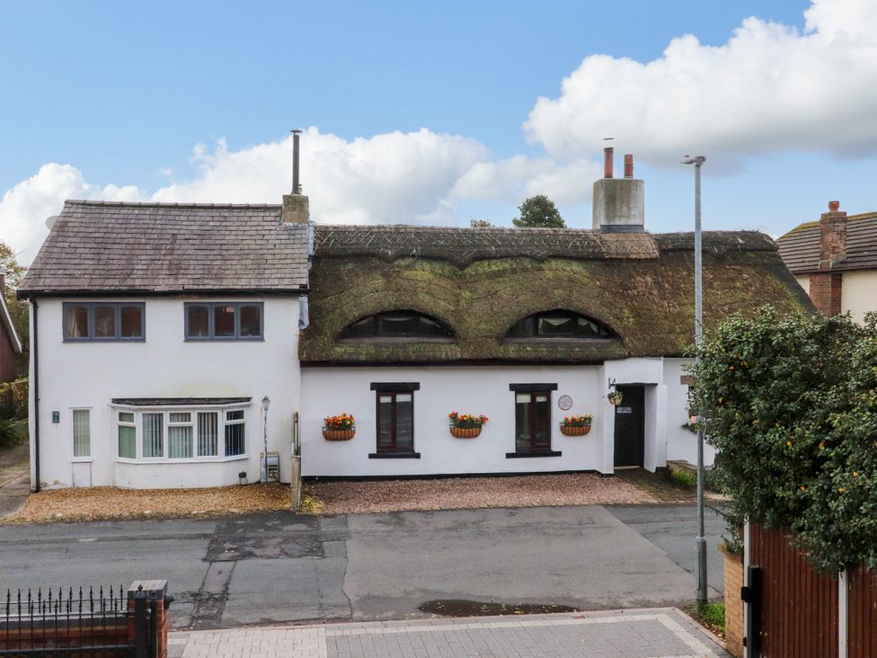 A house with a thatched roof and flower pots at The Thatched Cottage in Preston