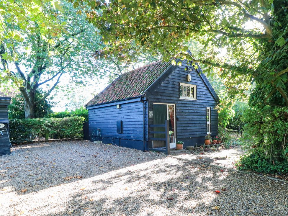 A black wooden building with a gravel driveway at Corner Barn North Burlingham near Blofield