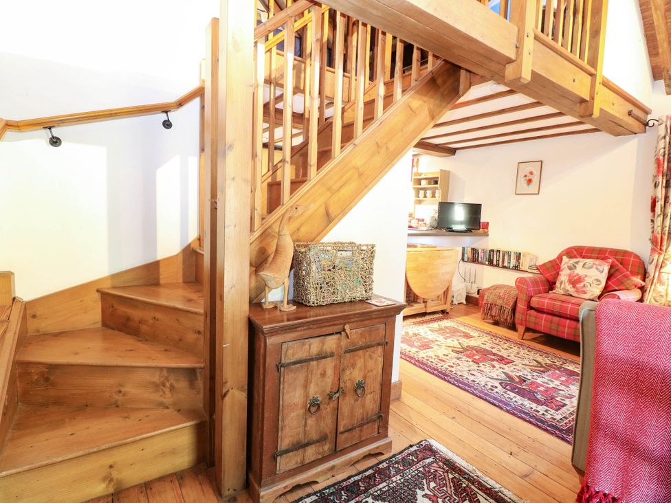 A living room with a staircase and wooden furniture at Corner Barn North Burlingham near Blofield