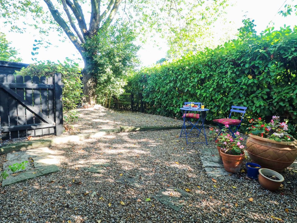 A garden with a gravel path and a table with chairs at Corner Barn North Burlingham near Blofield