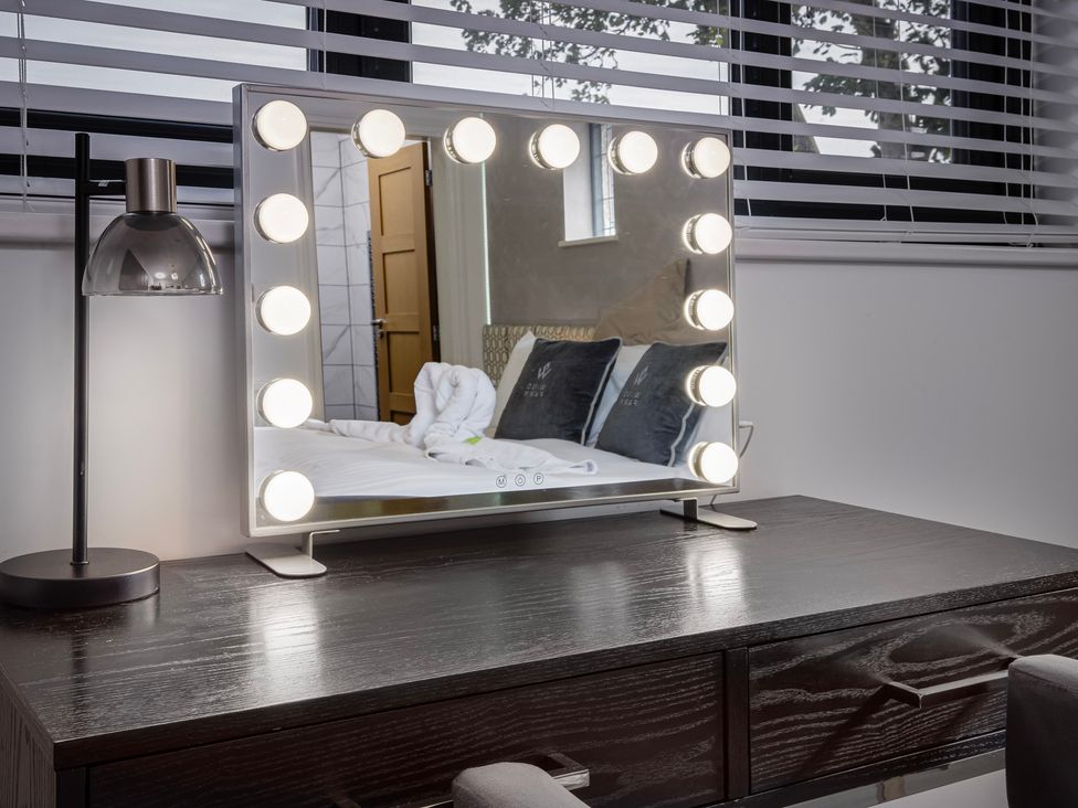 A vanity mirror with lights and a lamp on a desk at Wind Farm