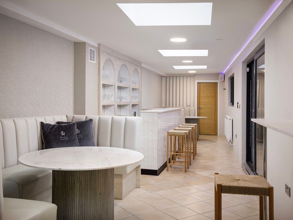 A snug area with a round table, chairs, and bar counter at Wind Farm 