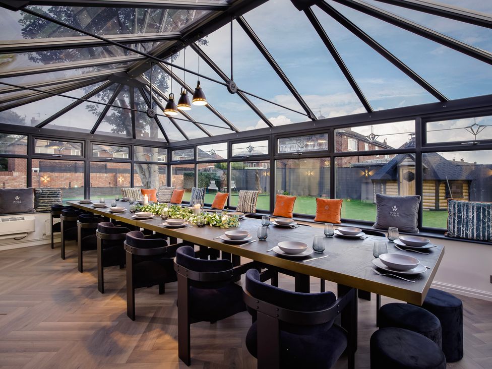 A dining area with a large table and chairs in a conservatory at Wind Farm