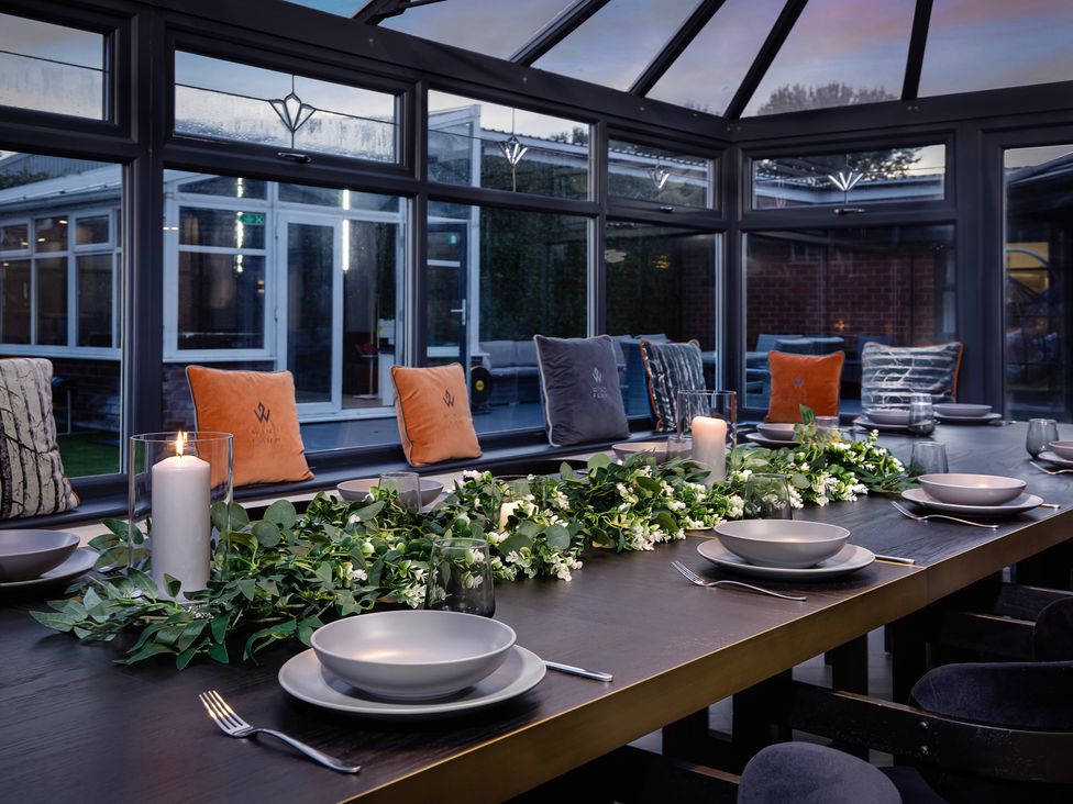 A dining table set with plates and candles in a conservatory at Wind Farm