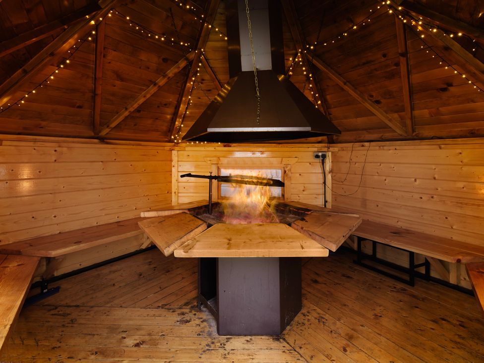A fireplace and wooden benches in a cabin at Wind Farm 
