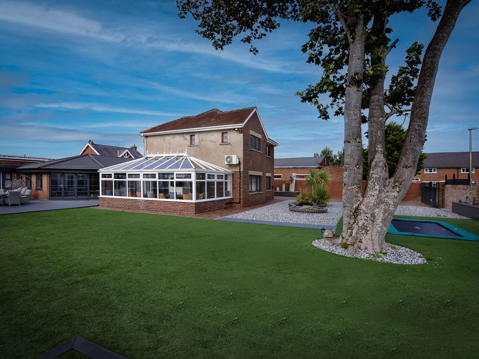 A garden with a conservatory and lush grass at Wind Farm