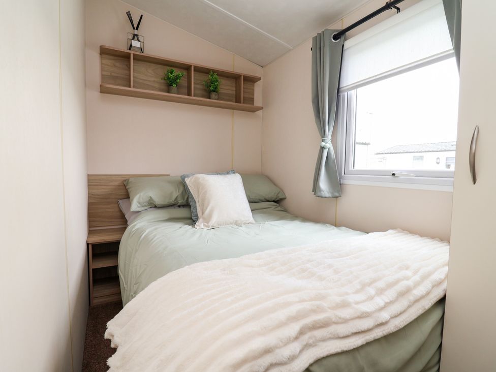 A bedroom with a bed, shelf, and window at B54