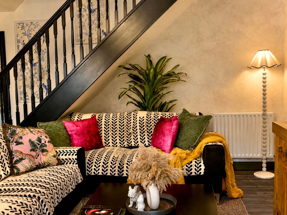 A living room with a sofa and staircase at Muddy Boots – La Petite Mews in Kirby Stephen