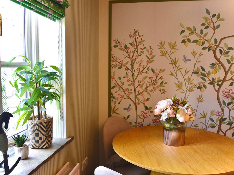 A dining room with a round table and flowers at Muddy Boots – La Petite Mews, Kirby Stephen