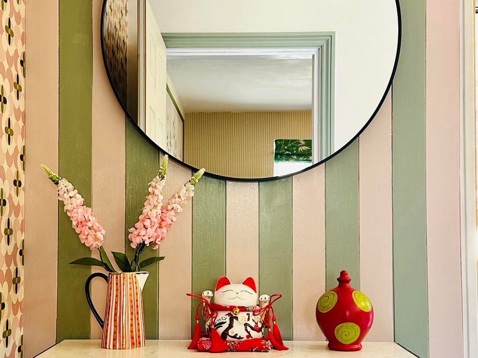 An entrance hall with a mirror and decorative items at Muddy Boots – La Petite Mews in Kirby Stephen
