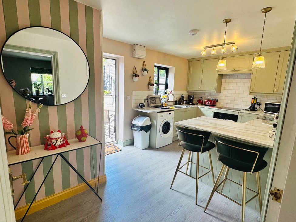 A kitchen with a washing machine and cabinets at Muddy Boots – La Petite Mews Kirby Stephen
