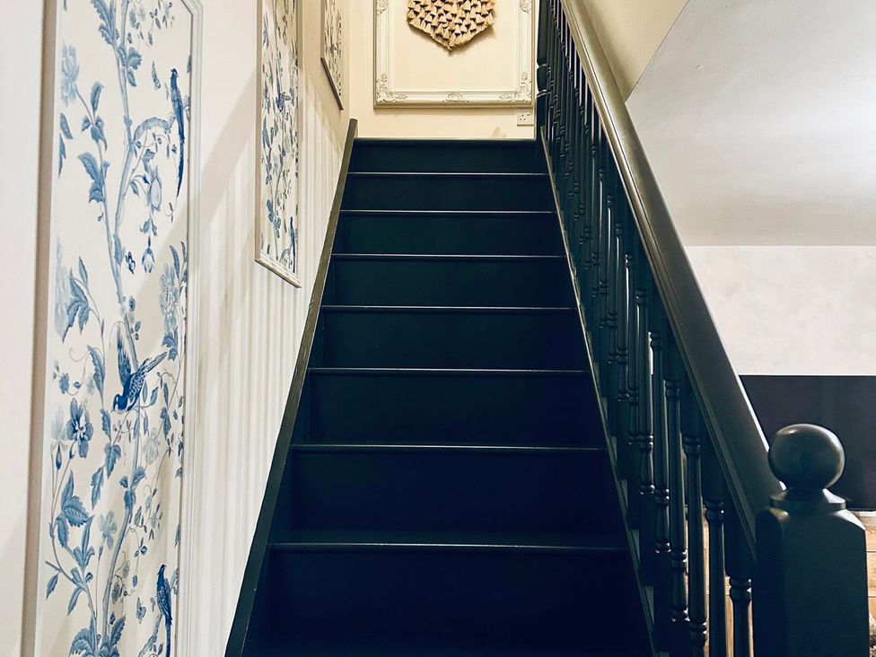 A staircase with wall decor and artwork at Muddy Boots – La Petite Mews Kirby Stephen
