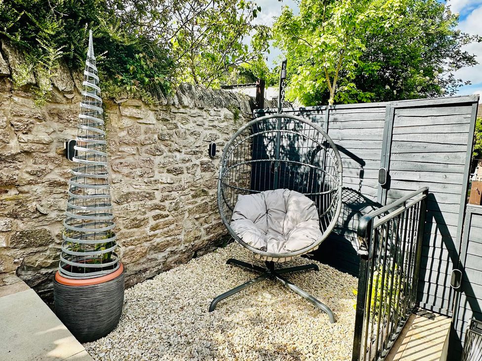 An outdoor area with a hanging chair and decorative tree at Muddy Boots – La Petite Mews in Kirby Stephen