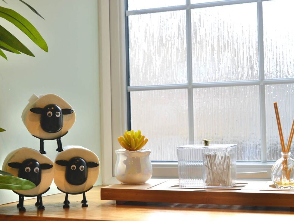 A kitchen window with sheep figurines and plants at Muddy Boots – Arcade Royale in Kirby Stephen
