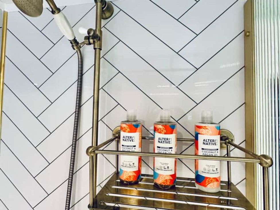 A bathroom with shampoo bottles on a shower rack at Muddy Boots – Arcade Royale in Kirby Stephen