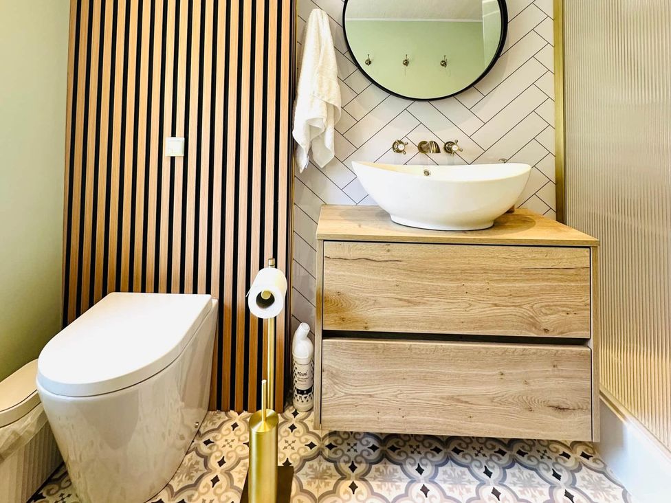 A bathroom with a toilet, sink, and mirror at Muddy Boots – Arcade Royale in Kirby Stephen