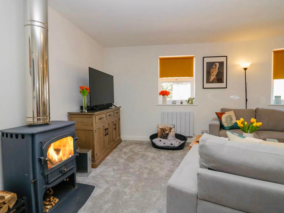 A living room with a wood stove and television at Muddy Boots – Scarpa in Kirkby Stephen
